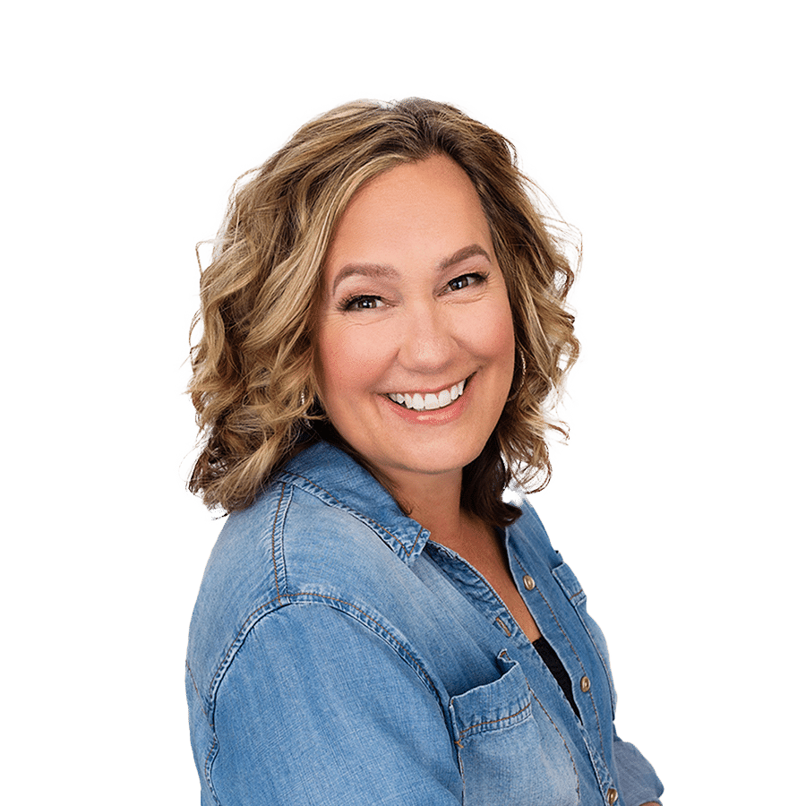 A smiling woman in a denim shirt.