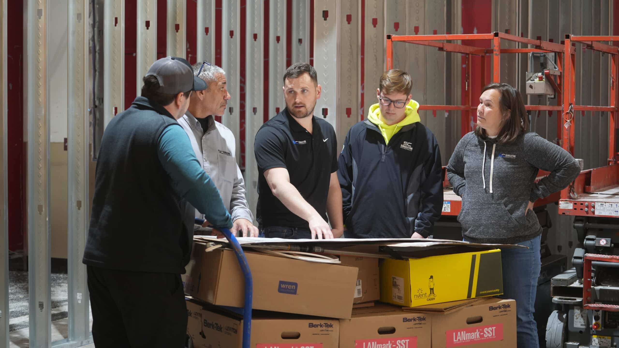 A group of people standing around boxes in a warehouse.