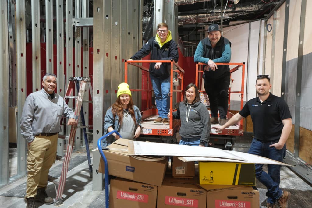 A group of people standing next to boxes in a construction area.