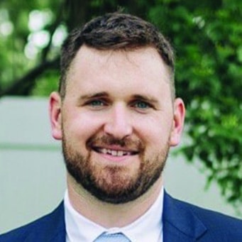 A man in a suit and tie smiles for the camera.