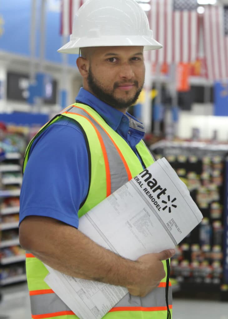 A man in a hard hat holding a document in a store.