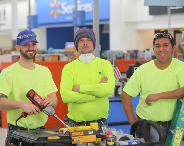 Three men in yellow shirts standing in a walmart store.